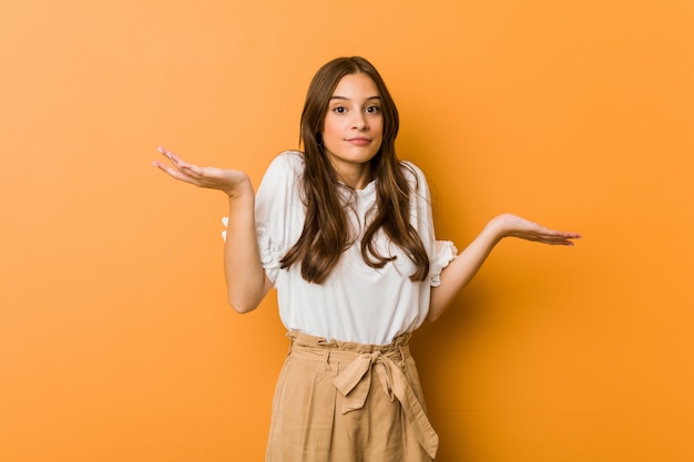 Young caucasian woman doubting and shrugging shoulders in questioning gesture.