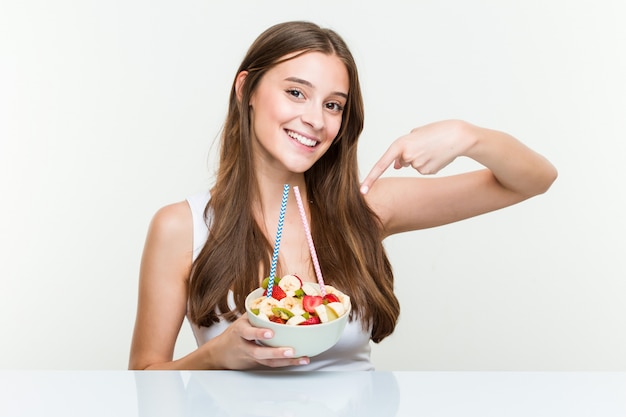 ストローでフルーツボウルを飲む若い白人女性。健康的な生活 。