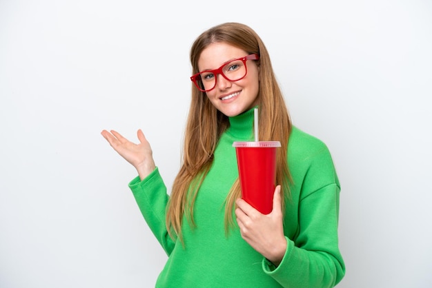 Photo young caucasian woman drinking soda isolated on white background extending hands to the side for inviting to come