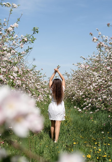 Young caucasian woman enjoying the flowering of an apple trees