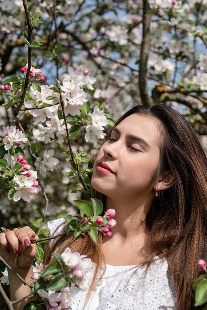 Young caucasian woman enjoying the flowering of an apple trees