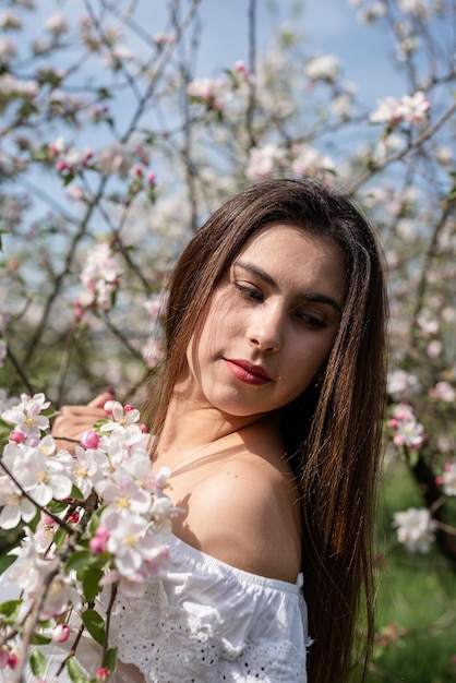 Young caucasian woman enjoying the flowering of an apple trees