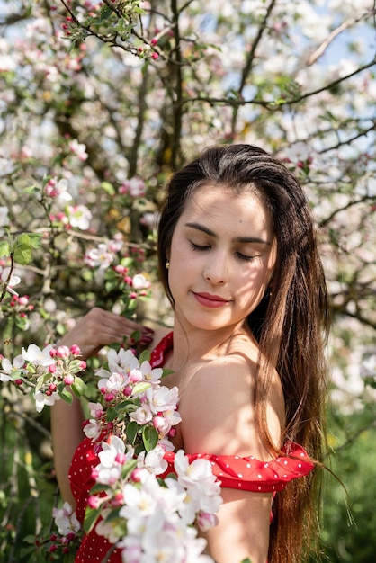 Young caucasian woman enjoying the flowering of an apple trees