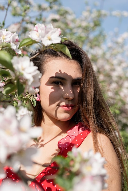 Young caucasian woman enjoying the flowering of an apple trees