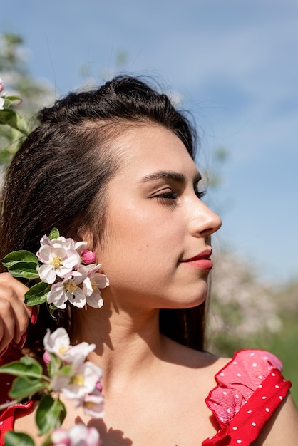 Young caucasian woman enjoying the flowering of an apple trees