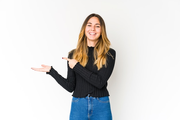 Young caucasian woman excited holding a copy space on palm.