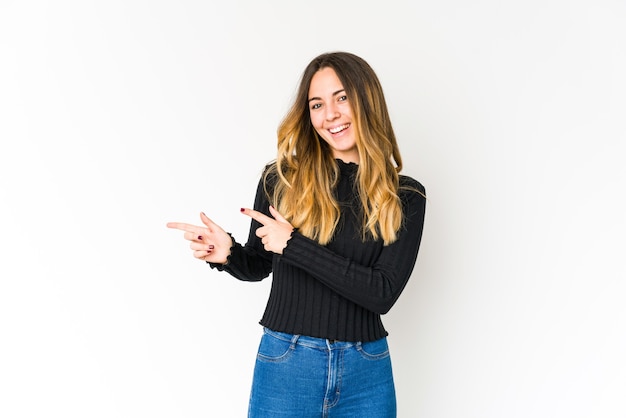 Young caucasian woman excited pointing with forefingers away.