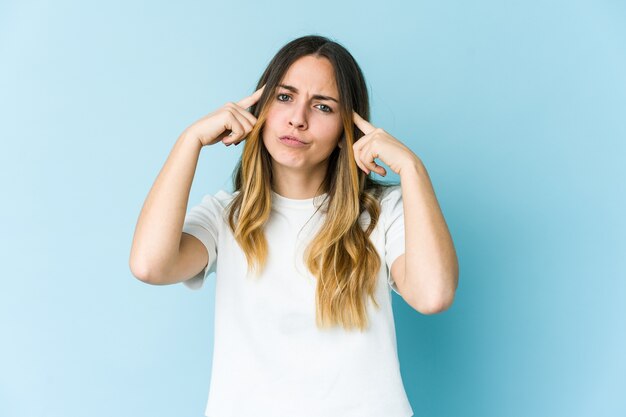 Young caucasian woman focused on a task, keeping forefingers pointing head.