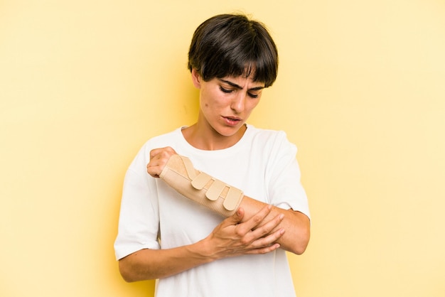 Young caucasian woman hand sling isolated on yellow background