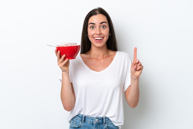 Young caucasian woman having breakfast milk isolated on white background pointing up a great idea