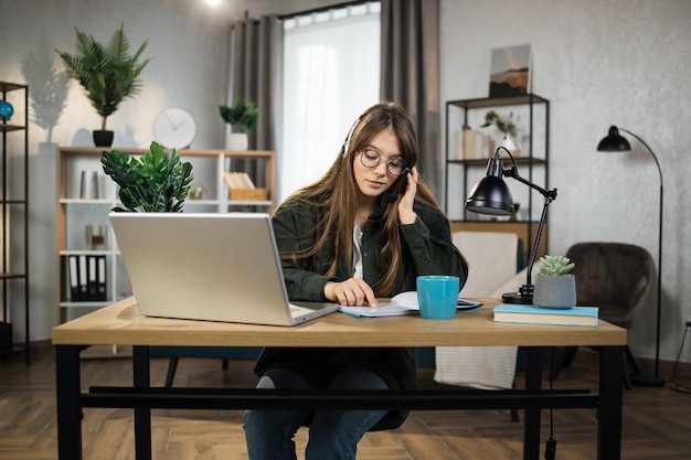 Young caucasian woman in headset sitting at desk with laptop and talking during video call