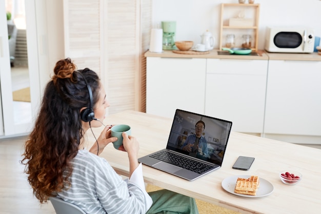 Young Caucasian woman and her Asian male colleague working together on project discussing it during video call