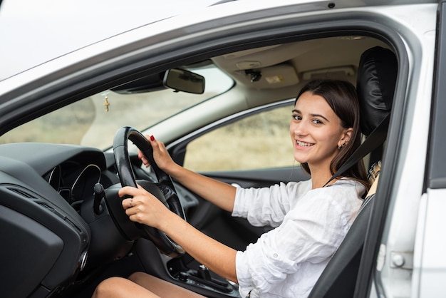 若い白人女性がステアリングホイールを握って車を運転している