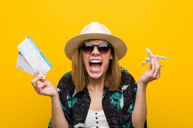 Young caucasian woman holding air tickets very happy.