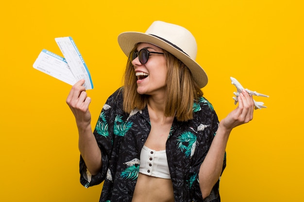 Young caucasian woman holding air tickets very happy.