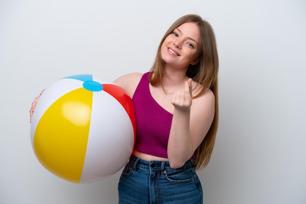 Young caucasian woman holding beach ball isolated on white background making money gesture