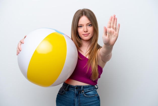 Young caucasian woman holding beach ball isolated on white background making stop gesture