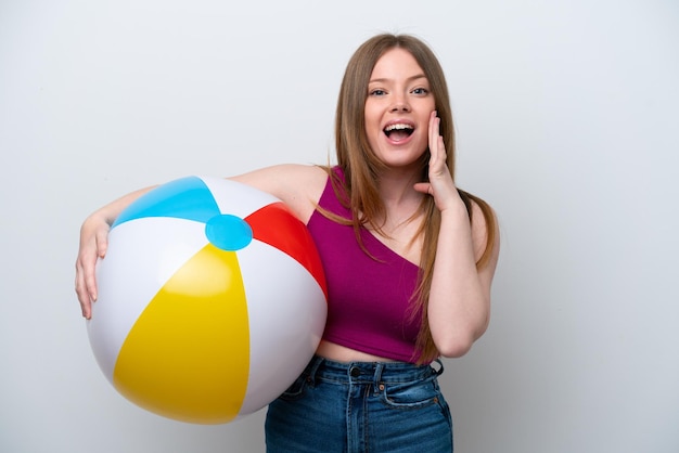 Young caucasian woman holding beach ball isolated on white background with surprise and shocked facial expression