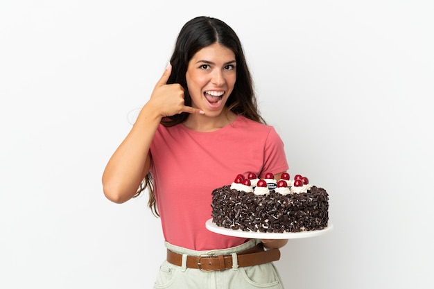 Young caucasian woman holding birthday cake isolated on white background making phone gesture. Call me back sign