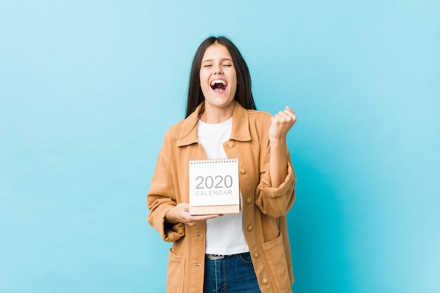 Young caucasian woman holding a calendar cheering carefree and excited