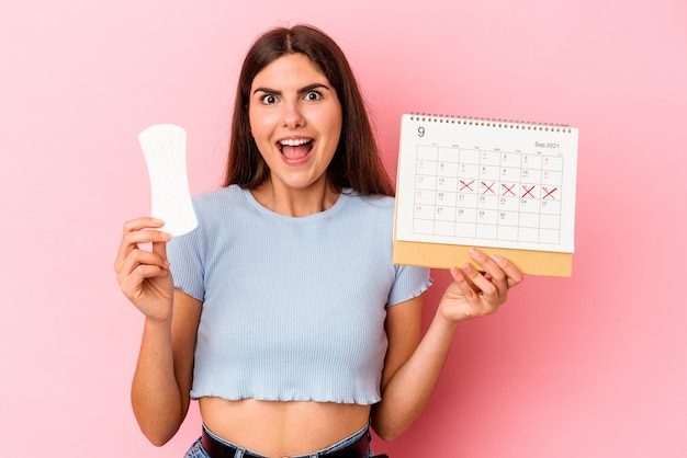 Foto giovane donna caucasica che tiene un calendario e un impacco isolato su sfondo rosa