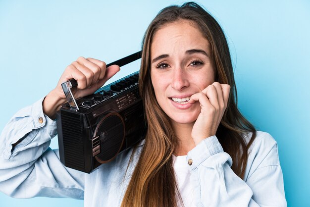 Young caucasian woman holding a cassete isolated biting fingernails, nervous and very anxious.