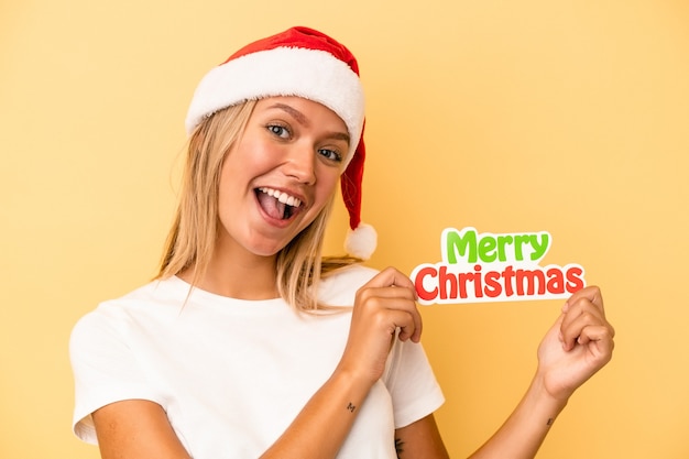 Young caucasian woman holding a christmas props isolated on yellow background