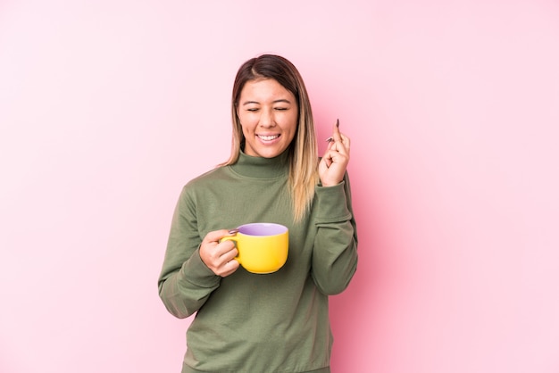 Young caucasian woman holding a coffee crossing fingers