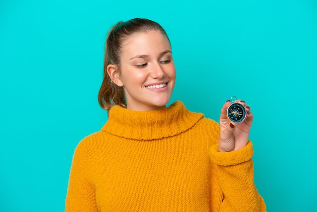 Young caucasian woman holding compass isolated on blue background with happy expression