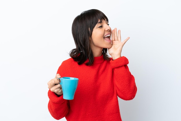 Young caucasian woman holding cup of coffee isolated on white background shouting with mouth wide open to the side