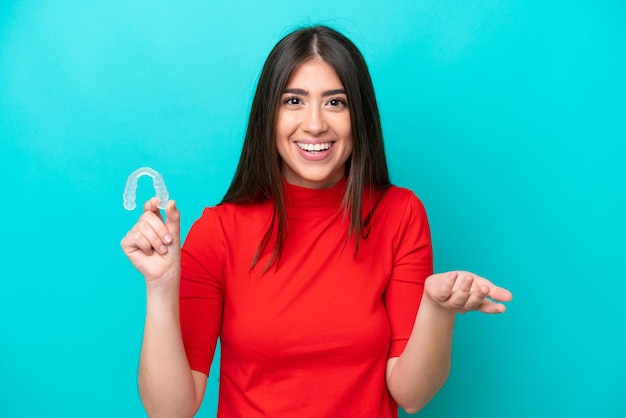 Young caucasian woman holding a envisaging isolated on blue background with shocked facial expression