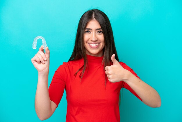 Young caucasian woman holding a envisaging isolated on blue background with thumbs up because something good has happened