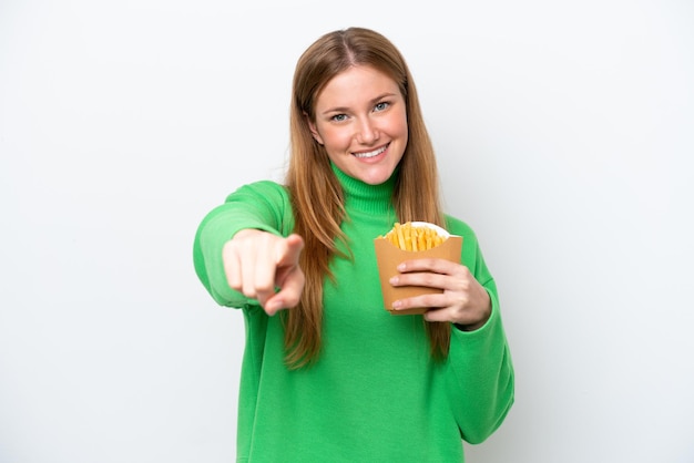 Young caucasian woman holding fried chips isolated on white background points finger at you with a confident expression