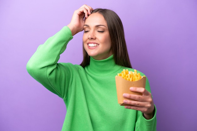 Young caucasian woman holding fried chips on purple background smiling a lot