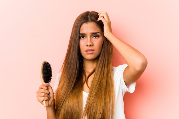 Young caucasian woman holding an hairbrush being shocked, she has remembered important meeting.