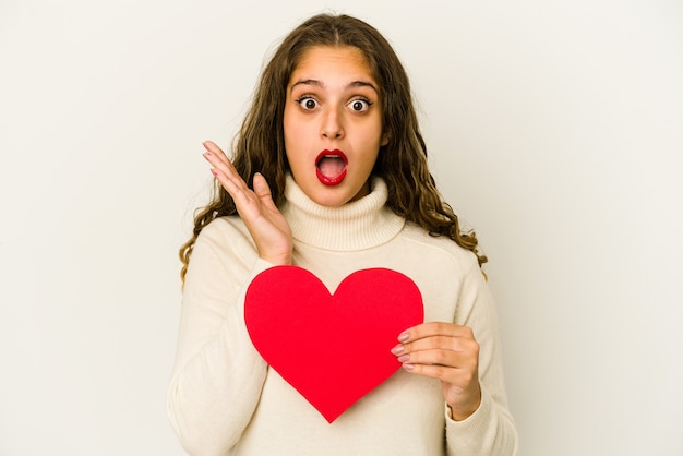 Young caucasian woman holding a heart valentines day shape isolated surprised and shocked.