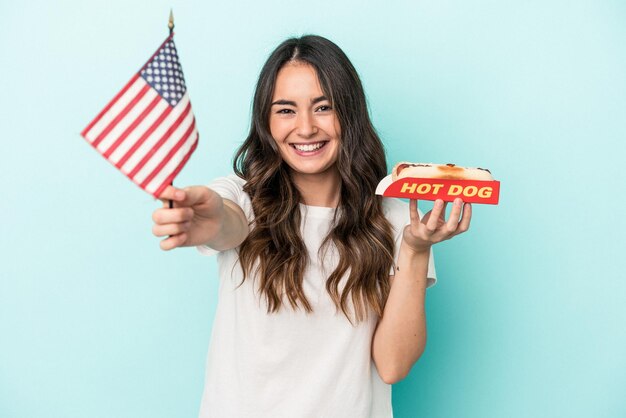 Young caucasian woman holding a hot dog isolated on blue background