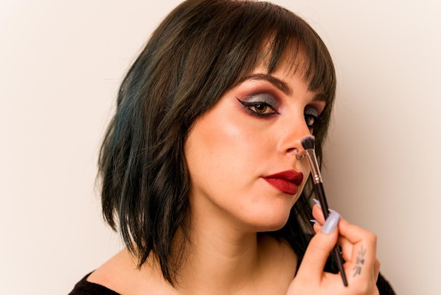 Young caucasian woman holding makeup brush isolated on pink background