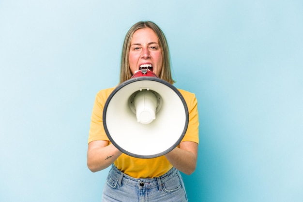 Photo young caucasian woman holding a megaphone isolated on blue background