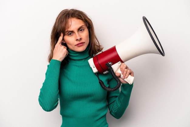 Young caucasian woman holding a megaphone isolated on white background pointing temple with finger thinking focused on a task