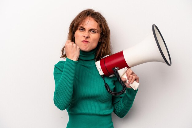 Young caucasian woman holding a megaphone isolated on white background showing fist to camera aggressive facial expression