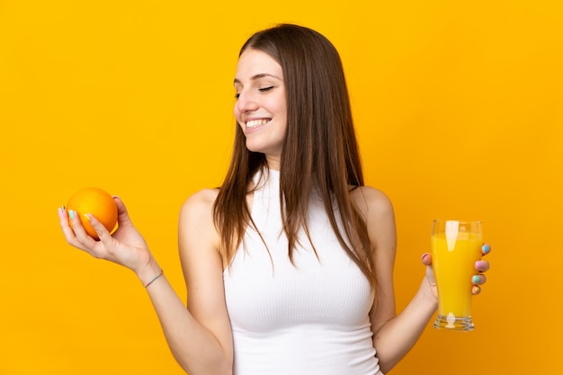 Young caucasian woman holding an orange isolated on orange