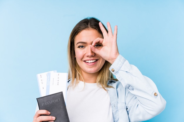 Young caucasian woman holding a passport isolated excited keeping ok gesture on eye.