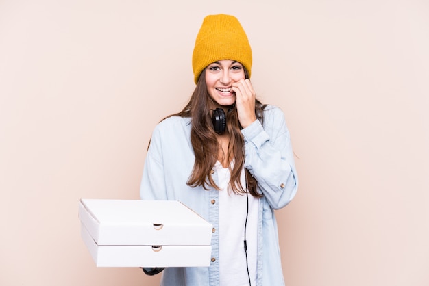 Young caucasian woman holding pizzas biting fingernails, nervous and very anxious.