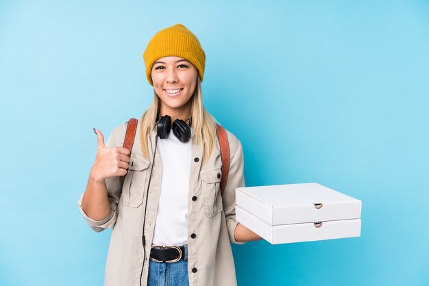 Young caucasian woman holding pizzas isolated smiling and raising thumb up