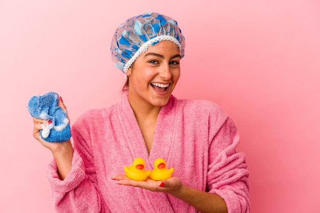 ピンクの背景で隔離のプラスチック製のアヒルを保持している若い白人女性