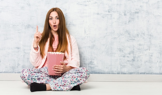 Young caucasian woman holding a popcorn bucket having some great idea, concept of creativity.