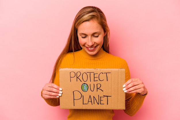 Young caucasian woman holding protect our planet placard isolated on pink background