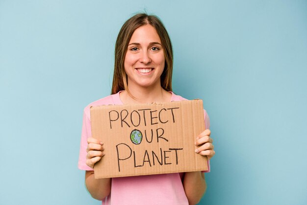 Молодая кавказская женщина держит плакат "Защити свою планету" на синем фоне