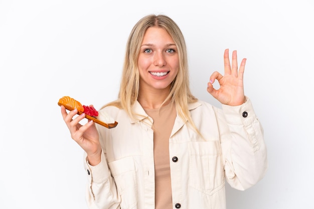 Young caucasian woman holding sashimi isolated on white background showing ok sign with fingers